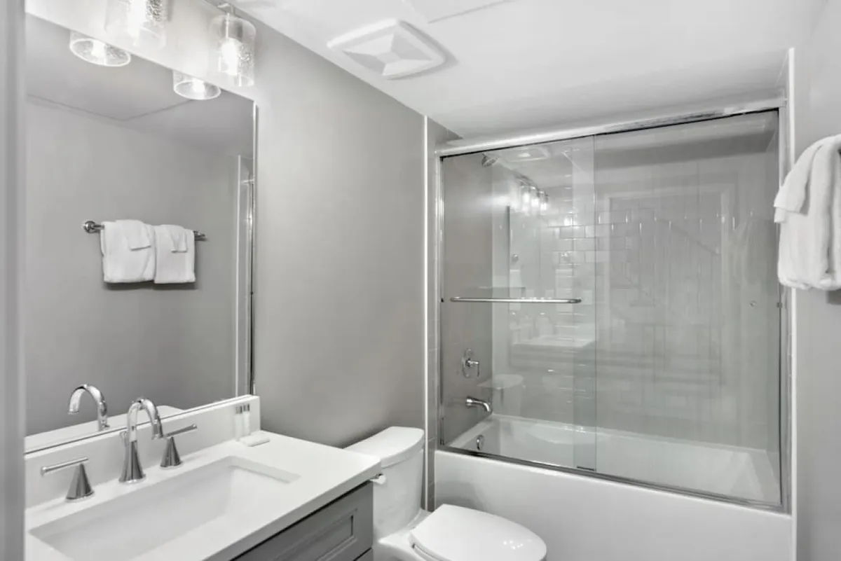A modern bathroom with a spacious sink, large mirror, and glass shower enclosure. The clean lines and ample natural light create an inviting, fresh space for self-care and daily routines.