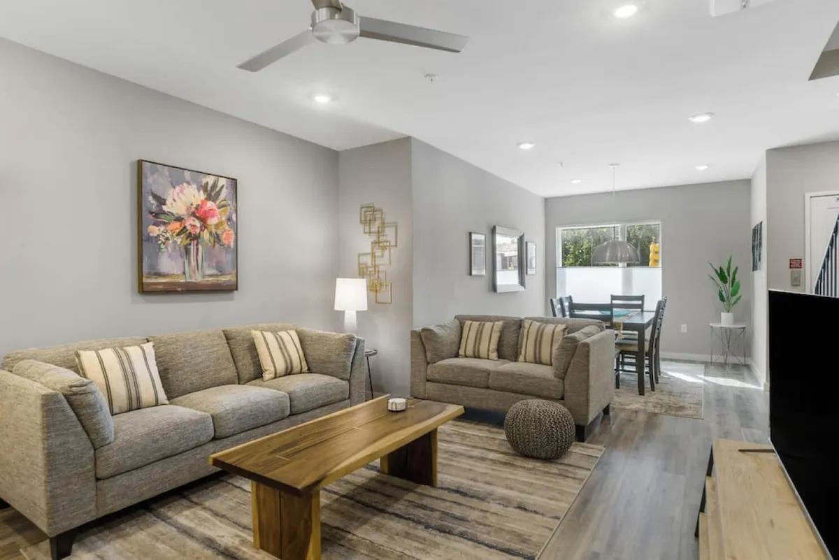 A cozy, inviting living and dining area with comfortable sofas, a stylish coffee table, a dining space, and tasteful artwork. The setting is ideal for relaxing after work, entertaining friends, or enjoying intimate gatherings, highlighting the home’s ability to balance productivity and downtime in style.
