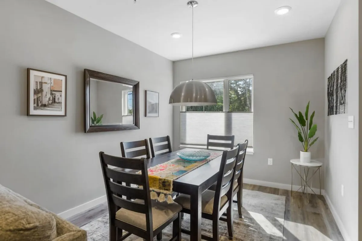 A stylish dining area with a central table, pendant light, framed artwork, and a potted plant, creating a welcoming ambiance for meals and celebrations. The layout accommodates groups, reinforcing the home’s suitability for special gatherings.