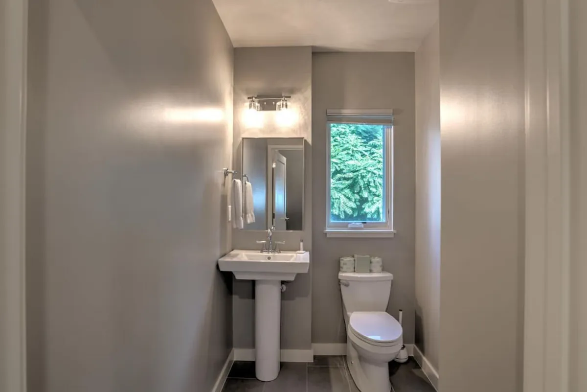 A compact, stylish half bath with a modern sink, toilet, and a window letting in natural light. The design is calm and refreshing, adding practical convenience to the main living level.