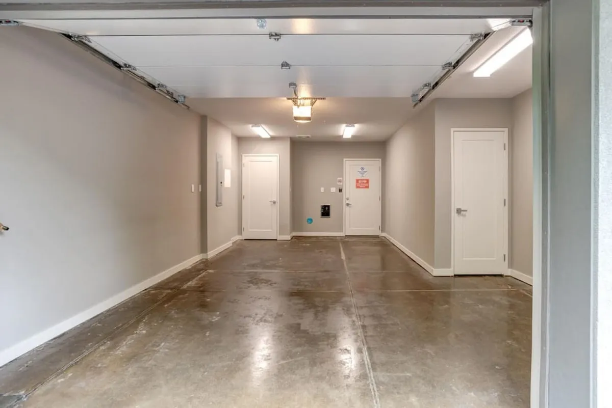 A practical garage space with prominent garage doors, a well-lit environment, and visible entry doors. The space has a utilitarian feel, suitable for parking vehicles and storing items, reinforcing the sense of arrival and secure beginnings mentioned in the section.